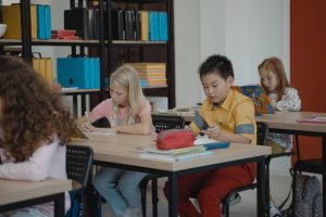 Children in a classroom setting, focusing on reading and writing activities.
